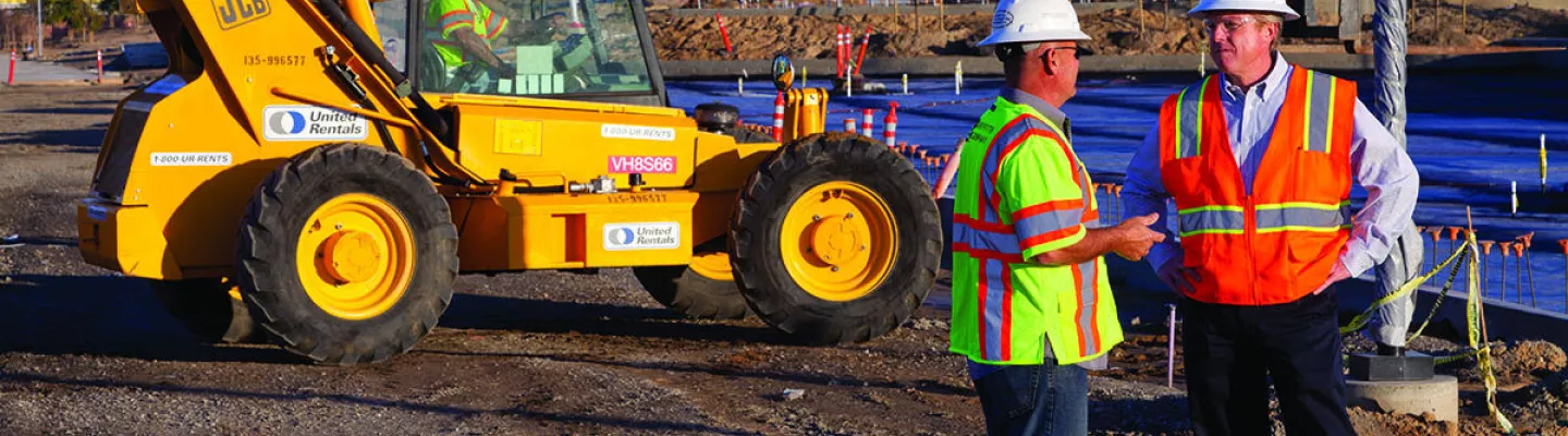 Discussing Plans Near Earthmoving Equipment