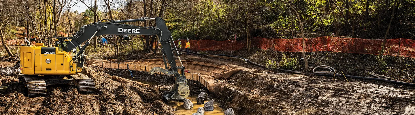 Yellow John Deere excavator digging in the dirt