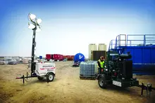 light towers at a jobsite with a man working on a pump